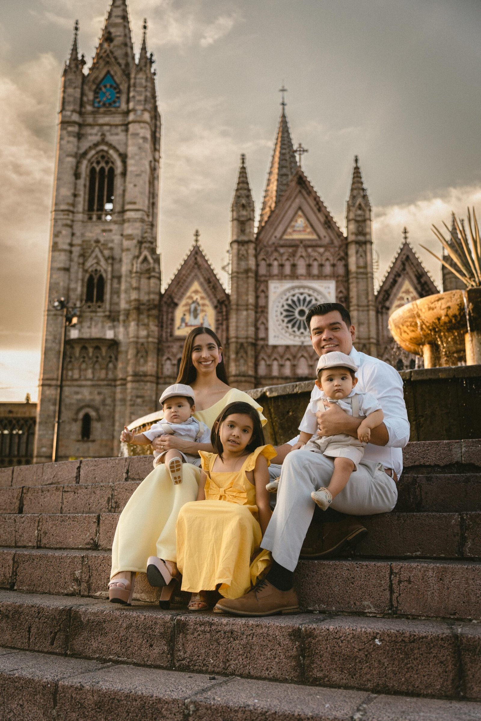 A family of five poses on cathedral steps with smiles at sunset.